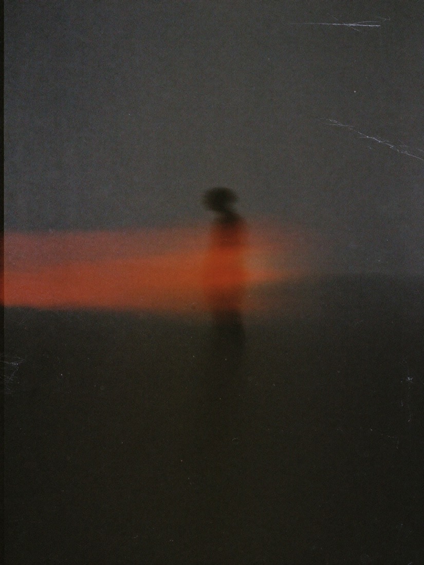 Motion study: blurred figure crossed by a band of red light, film grain